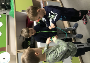 Trzej chłopcy podczas zawodów w nawlekanie sznurków.