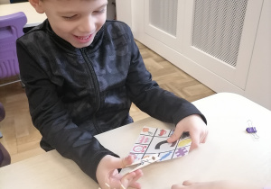Chłopiec zaznaczający na karcie obrazki pasujące do danej litery.