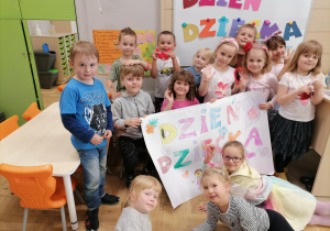 Dzieci pozują z dużym kolorowym plakatem z napisem: Dzień Dziecka