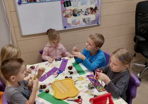 Grupa dzieci przy stoliku tworzy kasztanowe ludziki