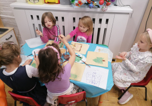 Grupa dziewczynek maluje czekoladą po waflach.