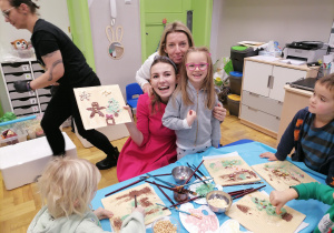 Dziewczynki oraz dwie wychowawczynie pozują do zdjęcia z obrazem malowanym za pomocą czekolady.