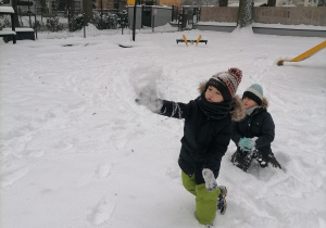 Dwóch chłopców bawi się w śniegu.