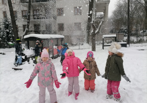 Cztery dziewczynki rzucają śniegiem w górę.