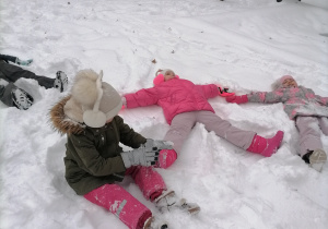 Dzieci robią orły na śniegu.