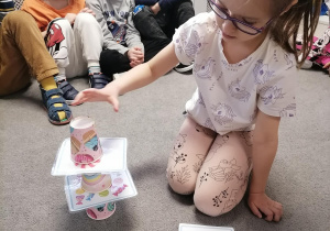 Dzieci nazywają słodkości na kartach i układają wieżę z kubeczków.