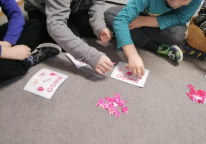 Dzieci na dywanie grają w grę bingo.