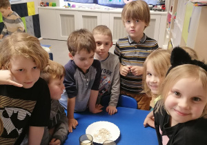 Dzieci przy stoliku omawiają proces wyrastania ciasta drożdzowego.