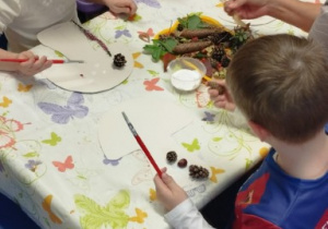 Dzieci wyklejające kształt grzybka za pomocą darów jesieni.
