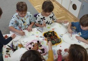 Dzieci wyklejające kształt grzybka za pomocą darów jesieni.