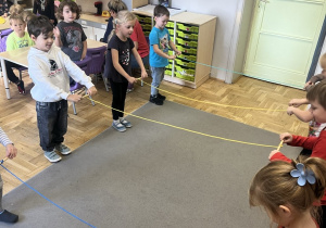 Grupa dzieci zwijająca sznurki na patyczki.