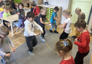 Grupa dzieci zwijająca sznurki na patyczki.