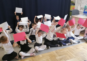 Grupa dzieci tańcząca z biało-czerwonymi kartkami.