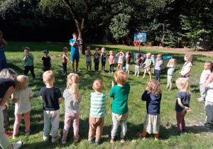 Grupa dzieci tworząca koło w ogrodzie przedszkolnym.