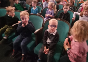 Dzieci siedzące na krzesłach w teatrze.