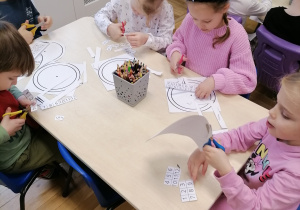 Dzieci wycinające zegary przy stoliku.