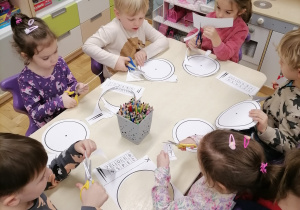 Dzieci wycinające zegary przy stoliku.