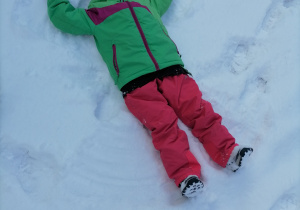Dziecko robiące orzełka na śniegu.