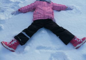 Dziecko robiące orzełka na śniegu.