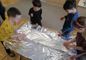 Dzieci bawiące się lodem i śniegiem na folii aluminiowej.