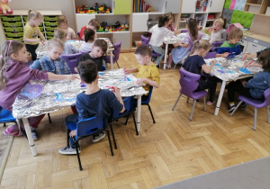 Dzieci malujące farbami po folii aluminiowej.