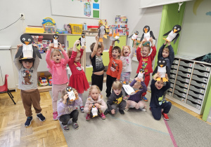 Grupa dzieci trzymająca wykonane przez siebie pingwiny.