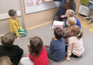 Dzieci siedzące na dywanie i słuchające historii powstania pizzy.