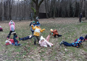 Dzieci wykonujące ćwiczenia ruchowe w ogrodzie.