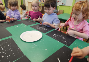 Dzieci malujące przy stoliku.