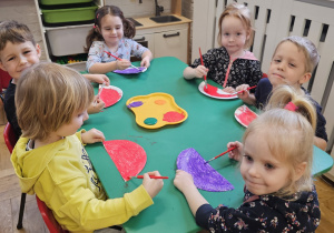 Dzieci malujące farbami przy stoliku.