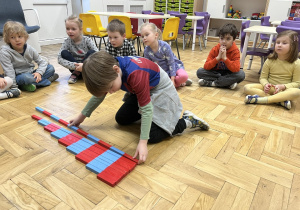 Chłopiec układający belki Montessori