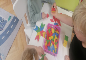 Dzieci przy toliku układają figury geometryczne