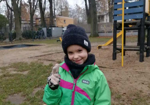 Dziewczynka pozuje uśmiechnięta do zdjęcia w ogródku