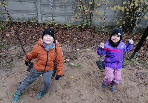 Dziewczynka z chłopcem bujają się na huśtawkach