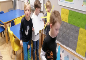 Chłopcy trzymają krople deszczu, chmurę, słońce i trawę