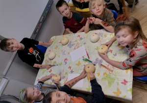 Dzieci siedzą przy stoliku z białymi dyniami