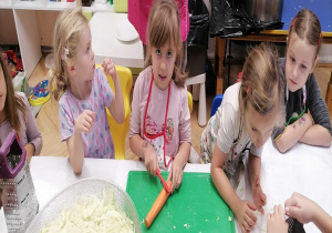 Dzieci przy stoliku przygotowują marchewki i kapustę