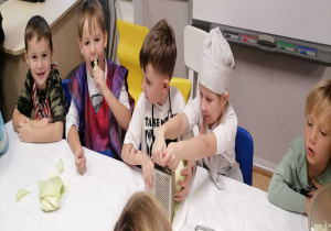 Dzieci przy stolikach próbują startych produktów