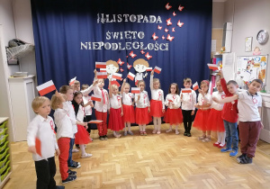 Dzieci w strojach biało czerwonych machają flagami podczas uroczystości