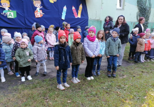 Dzieci czekają na wytęp przed przedszkolem w ogrodzi