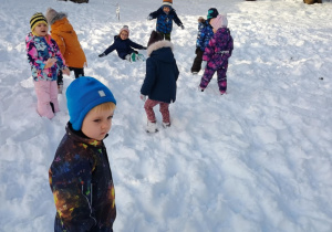 Dzieci rzucają się śnieżkami w ogrodzie przedszkolnym