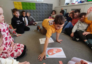 Dzieci na dywanie układają figury geometryczne