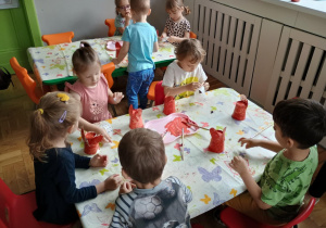 Dzieci malują brązową farbą zajączki wykonane z kubeczków