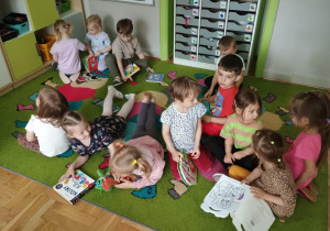 Dzieci na dywanie oglądają książeczki