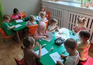 Dzieci siedzą przy stoliku i projektują swoją książkę