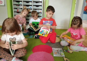 Dzieci oglądają książki na dywanie