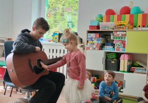 Dziewczynka próbuje grać na gitarze