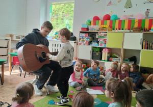 Chłopiec próbuje grać na gitarze