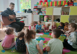 Dzieci słuchają gry na gitarze