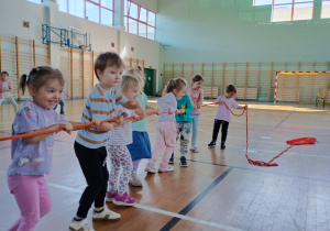 Dzieci na sali gimnastycznej ciągną linę